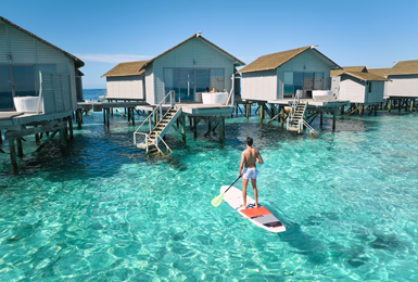 Stand up Paddler vor einer Vasservilla im Centara Ras Fushi auf den Malediven
